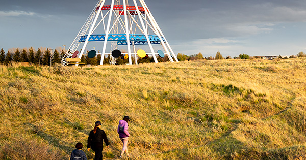 Medicine Hat Alberta Canada, May 13 2021: A family walks outdoors along a hiking trail in Seven Persons Coulee by the Sammis Tepee at sunset.