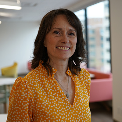 Brenda wearing an orange scattered star t-shirt and smiling towards camera